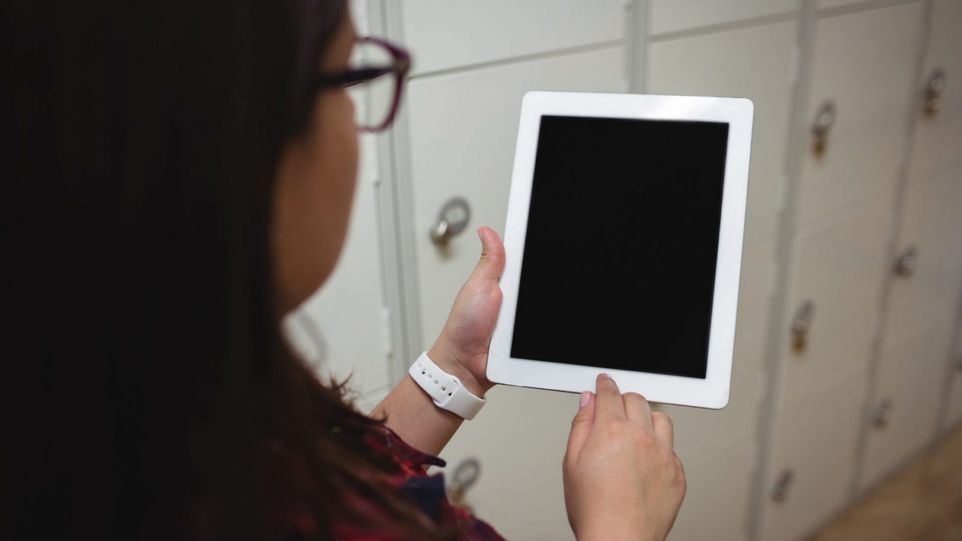 Female student using digital tablet in locker room